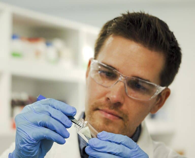 Researcher putting carefully a filter in a glass vial